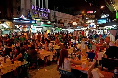 a crowd of people sitting at tables in a street at night at XX GO INN Khaosan - โกอินน์ ถนนข้าวสาร in Bangkok