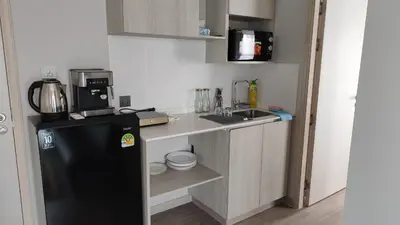 a small kitchen with a black refrigerator and a sink at Lumpini park chatuchak in Bangkok