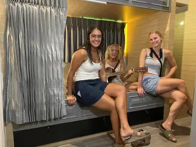 three girls sitting on a bed in a bathroom at SU SU khaosan hostels in Bangkok