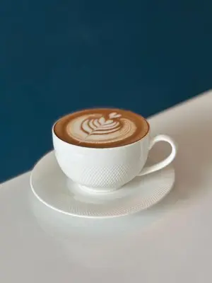 a cup of coffee sitting on a white plate at Belivin'98 Sense of Pier Sathorn Residence in Bangkok