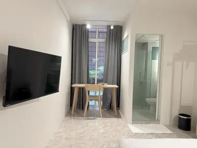 a room with a table and a tv and a bathroom at 95 Lodge in Bangkok