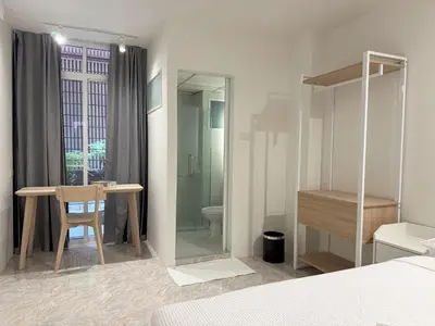 a bedroom with a bed and a table and a bathroom at 95 Lodge in Bangkok