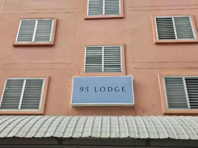a sign on the side of a pink building at 95 Lodge in Bangkok