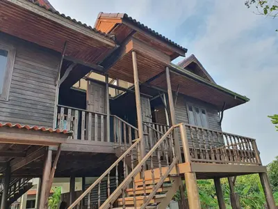 a large wooden house with a large deck at Baan Marrada Garden in Ban Pak Khlong Khwang
