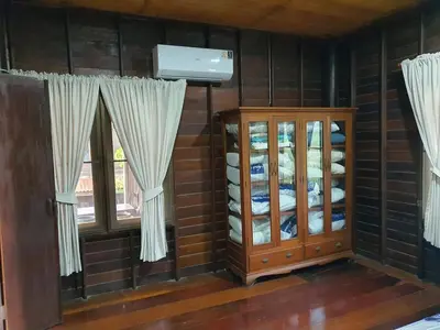 a room with a cabinet and windows with curtains at Baan Marrada Garden in Ban Pak Khlong Khwang