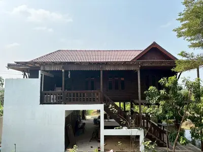a house with a wooden roof and a staircase at Baan Marrada Garden in Ban Pak Khlong Khwang