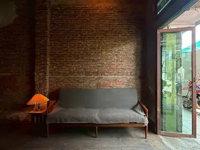 a brick wall with a bench next to a window at Yellow House in Bangkok