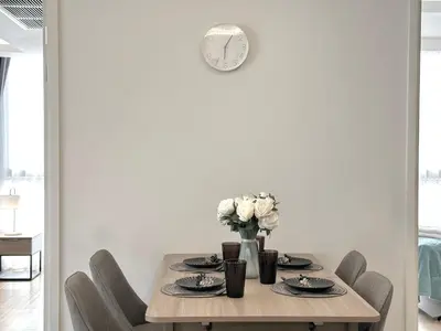 a dining room table with chairs and a clock on the wall at Circle31 #2BR Bangkok in Bangkok