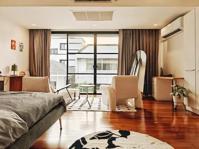 a bedroom with a bed and two chairs and a balcony at 4BR Modern Art Villa with Free Wi-Fi Netflix Vinyl in Bangkok