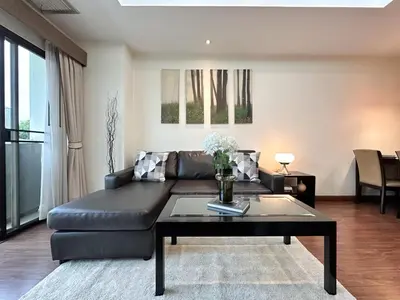 a living room with a black couch and a table at Vibrant Modern 57 SQM - Ultra Fast WiFi - BTS Thonglor in Bangkok