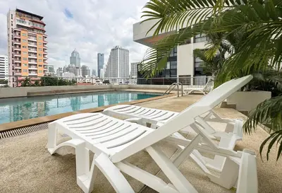 two white lounge chairs sitting next to a swimming pool at Nana SkyView Retreat 2 Bedroom 2 Bath Nana BTS in Bangkok