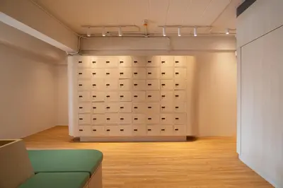 a room with a wall of lockers and a couch at BEAT Warii Hostel at Chaophraya River in Bangkok