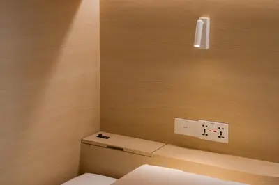 a bathroom with a toilet and a light on the wall at BEAT Warii Hostel at Chaophraya River in Bangkok