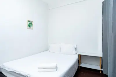 a bed with white sheets and pillows in a room at GO INN Siriraj Wang Lang - โก อินน์ ศิริราช ตลาดวังหลัง in Bangkok Noi