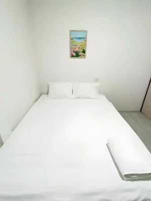 a white bed in a bedroom with a picture on the wall at GO INN Siriraj Wang Lang - โก อินน์ ศิริราช ตลาดวังหลัง in Bangkok Noi