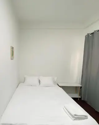 a bed with white sheets and pillows in a room at GO INN Siriraj Wang Lang - โก อินน์ ศิริราช ตลาดวังหลัง in Bangkok Noi
