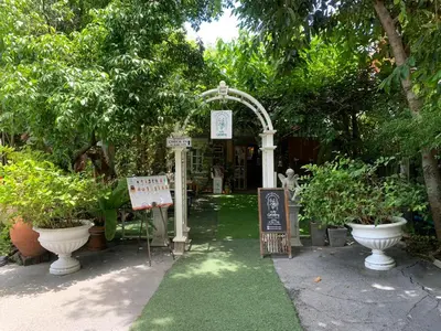 a garden with an arch and signs and trees at Ruennakornin Homestay in Ban Bang Muang