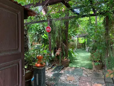 a walkway in a garden with plants and a stop sign at Ruennakornin Homestay in Ban Bang Muang