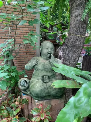 a statue of a little boy sitting next to a tree at Ruennakornin Homestay in Ban Bang Muang