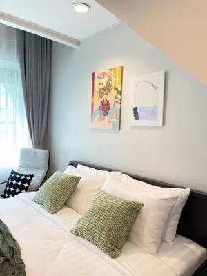 a bedroom with a white bed with two green pillows at Nueng Rana 113 Unique House in Chinatown 3BR 2BA in Samphanthawong
