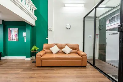 a brown couch in a room with a green wall at The Sleepyard Sathorn 11 in Bangkok