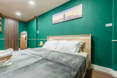 a bedroom with a green wall and a bed at The Sleepyard Sathorn 11 in Bangkok