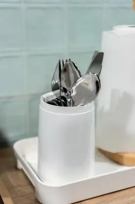a white container filled with utensils on a counter at The Sleepyard Sathorn 11 in Bangkok