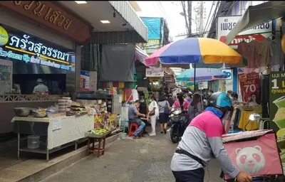 a group of people walking around a market with an umbrella at Wanglang Home in Bangkok Noi