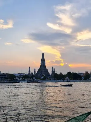 a view of a temple from the water at sunset at Wanglang Home in Bangkok Noi