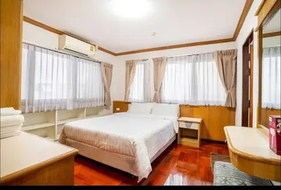 a bedroom with a white bed and windows at Baan Arthit in Bangkok