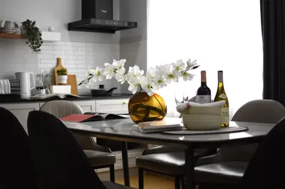 a table with a vase of flowers and bottles of wine at SiS at Sathorn St Louis in Bangkok