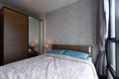 a bedroom with a bed and a brick wall at BRAND New Sukhumvit Condo Cozy BTS in Bangkok