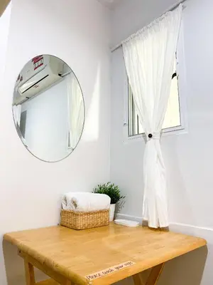 a mirror and a table in a room with a window at 1sabai in Bangkok