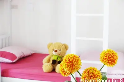 a teddy bear sitting on a bed with flowers at 1sabai in Bangkok