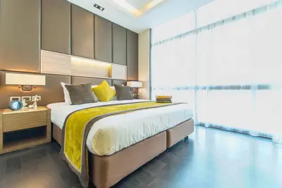 a bedroom with a large bed with a yellow blanket at Qiss Residence by Bliston in Bangkok