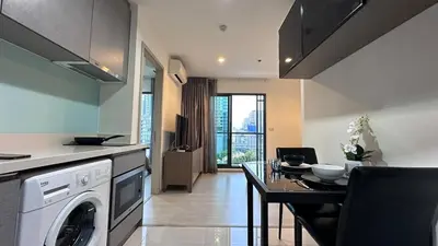 a kitchen with a washing machine and a dining table at Beautiful condo, BTS Thonglor, 5mins by walking in Bangkok