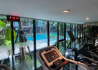 a gym with a view of a swimming pool at Lovely Condo-BTS Thong Lo 5mins in Bangkok