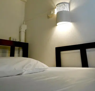 a bedroom with a white bed and a lamp at Les Fleurs Bangkok Hostel in Bangkok