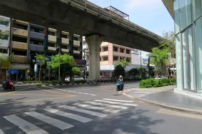 a person riding a scooter on a street under a bridge at Les Fleurs Bangkok Hostel in Bangkok