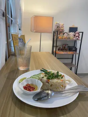 a white plate with food on a wooden table at Tktattoo63 in Tha Akatsayan Don Muang