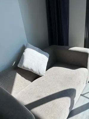 a couch with two pillows on it in a room at 1BR Free pool&gym fast WIFI Airport Link in Sathani Ban Hua Mak