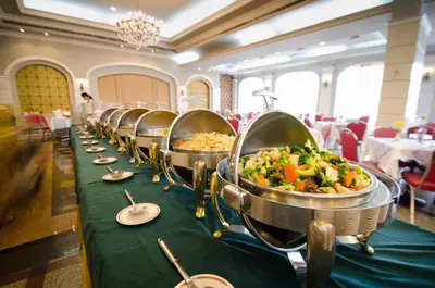 a row of buffet tables with bowls of food at Royal Rattanakosin Hotel - Near Grand Palace & Khaosan Road in Bangkok