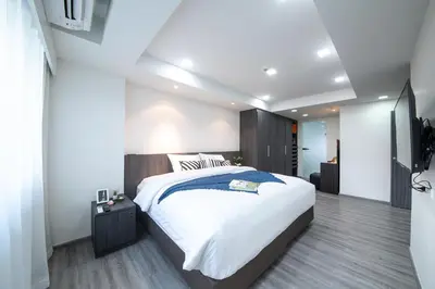 a bedroom with a large white bed and a television at Civic Park in Bangkok