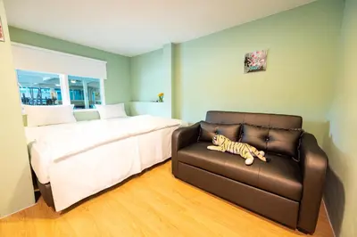 a bedroom with a bed and a couch with a stuffed tiger at GL Sport Club Serviced Residence in Bangkok