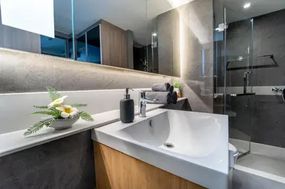 a bathroom with a white sink and a shower at 5 star Luxurious 1BD apt King Bed Thong Lor in Bangkok