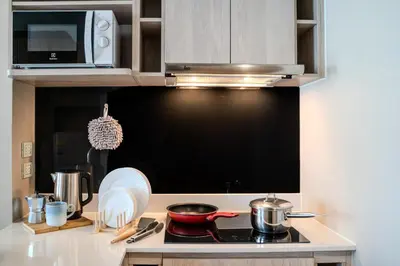 a kitchen with a stove top with a microwave at Luxury 2BR with Sky Pool & Gym Near BTS Thong lo in Bangkok