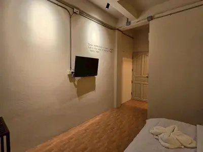 a room with a bed and a tv on a wall at Lhong Krung Hostel in Bangkok