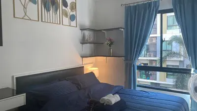 a bedroom with a blue bed and a window at Cozy Entire Apartment place in Ban Khlong Samrong