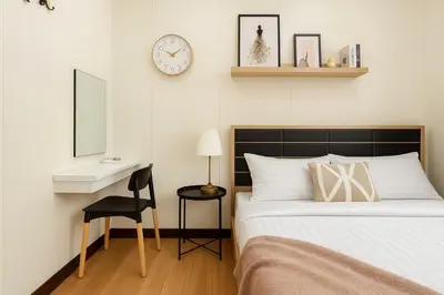 a bedroom with a bed and a desk and a clock at GM7 - Private House Downtown 2mins walk to metro in Bangkok