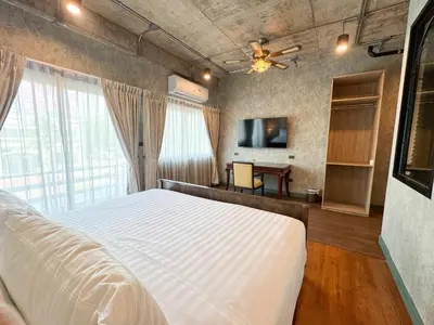 a bedroom with a white bed and a television at Nara Poshtel Sathorn in Bangkok